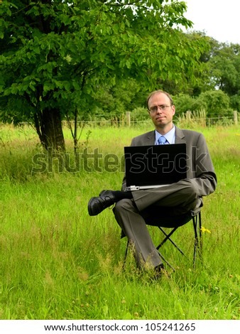 Green IT businessman working outdoor with laptop on green grass