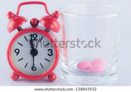 Red clock and pink tablet in prescription glass