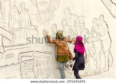VOLGOGRAD - SEPTEMBER 28:Tourists from Asia pose in front of figures describing feats of Russian soldiers on the walls of Mamayev Kurgan. September 28, 2014 in Volgograd, Russia.