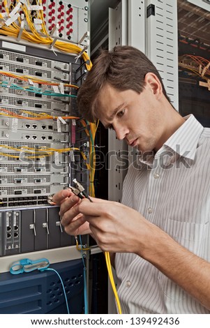 Network engineer in server room with optical patchcord