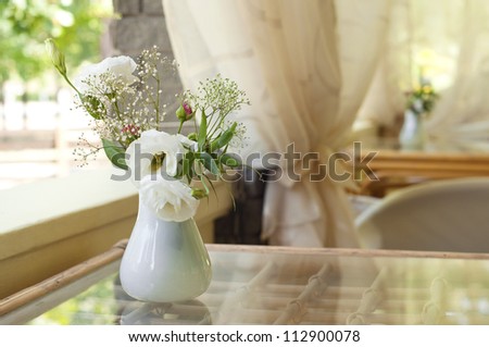 Closeup of rose flower bouquet in a vase on a sunny summer day in cafe. Main focus on flowers