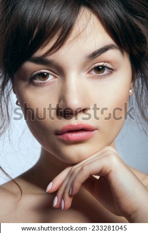 Pretty young woman with natural makeup and perfect skin looking at camera, lips half open. In studio