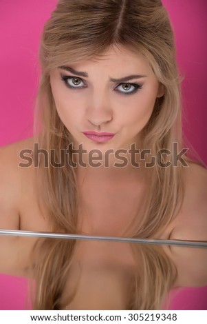 photo girl blonde hair, professional make-up with the reflection in the mirror on a pink background