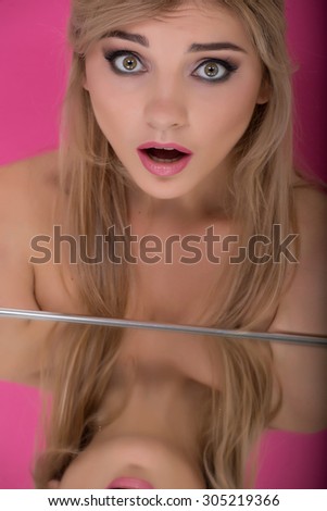 photo girl blonde hair, professional make-up with the reflection in the mirror on a pink background