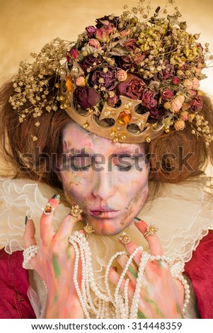 Studio art photo of the girl in the image of the Queen on a gold background. the art of makeup.
