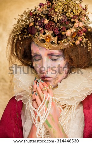 Studio art photo of the girl in the image of the Queen on a gold background. the art of makeup.