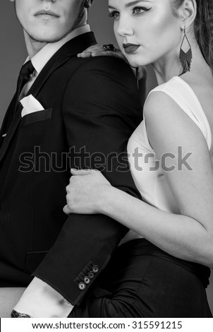 black and white Studio photos erotic young couple on black background. Girl in a dress, man in a business suit