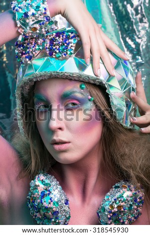 Studio photo of a girl in body art image - musical the girl in the hologram helmet and headphones with rhinestones on a dark background