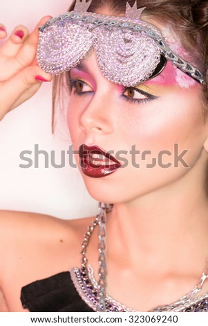 Studio photos - dark haired girl with stylish make-up art and additional accessories, with stylish glasses on bright reflecting background
