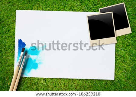 brush and paint scratch paper with frame photo on grass background