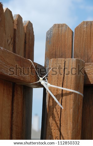 Temporary Fence Repair - An old wooden fence is held together with a makeshift solution - plastic zip ties.