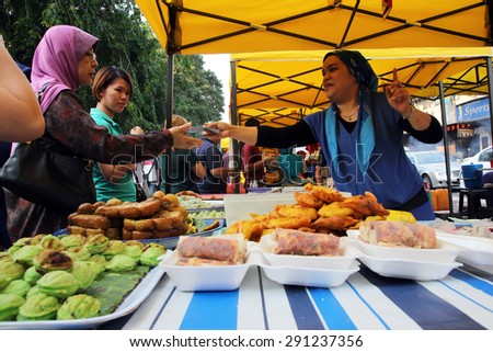 KUALA LUMPUR, MALAYSIA - JUNE 25, 2015 : Customers buying food from a stall at a ramadhan bazaar before breaking fast.