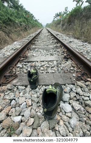 Pair of shoes on railroad tracks depicting lone solo travel