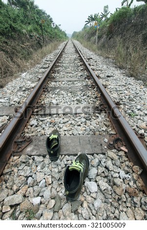 Pair of shoes on railroad tracks depicting lone solo travel