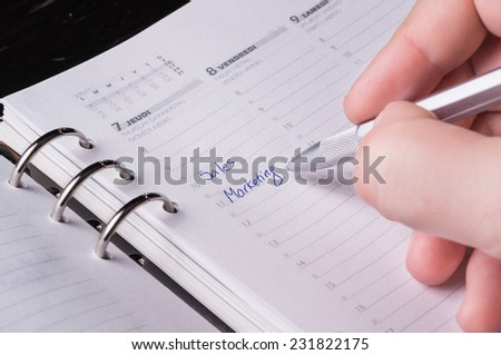 hand writing with silver pen on open business agenda