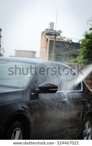 Gentle car washing. Modern compact car covered by water.