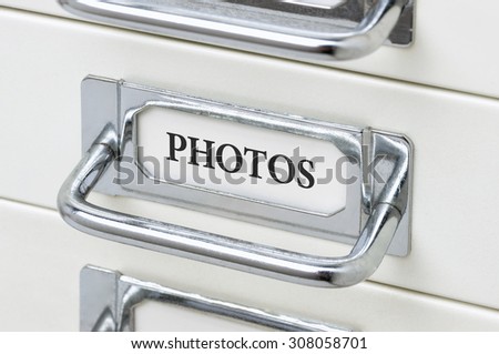 A drawer cabinet with the label Photos