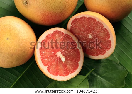 Ripe red grapefruits, whole and cut, on the palm leaf