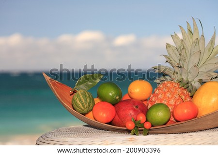 Tropical fruit basket with pineapple, mango, grapefruit, orange fruit, lemon, lime, tangerine, sea on the background. Hawaii, Maui, USA