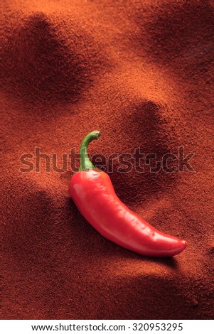 Chili pepper pod on chili powder background, full frame