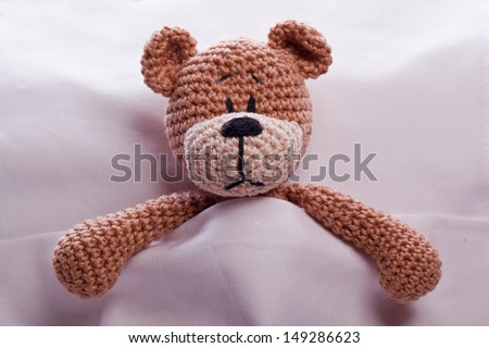 brown teddy bear lyiing sick in bed