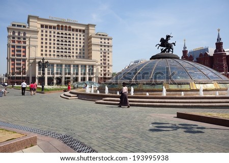 MOSCOW - MAY 19: Fountain World Clock, glass dome decorated with sculpture of St. George, Four Seasons Hotel Moscow building and walking people on May 19, 2014 on Manezh Square in Moscow.