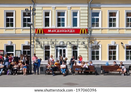 MOSCOW - MAY 31: People sitting on benches near McDonalds restaurant building on Tolmachesvsky street on May 31, 2014 in Moscow.