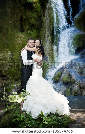 Lovely smiling couple at their wedding photo session near a waterfall