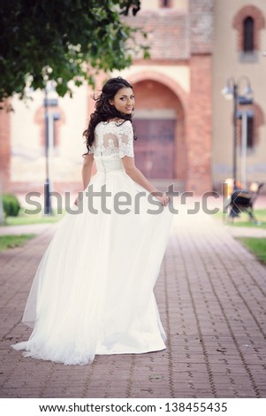 Happy and delicate bride running in her wedding day, in front of the church