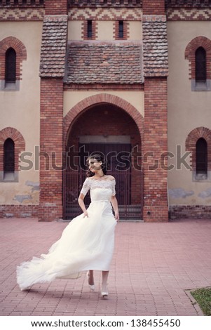 Happy and delicate bride running in her wedding day, in front of the church