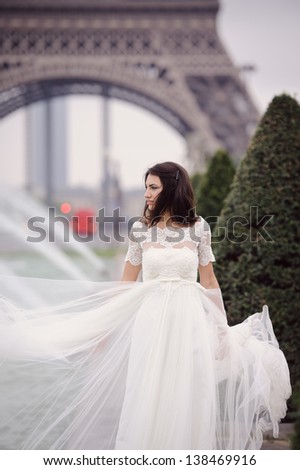 Beautiful delicate bride smiling on her wedding day in Paris with her dress in the air