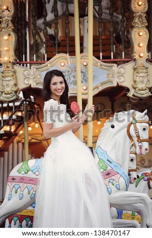 Beautiful delicate bride smiling in a carousel on her wedding day in Paris