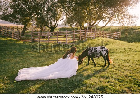 Stunning and beautiful bride dreaming near her horse in her wedding day