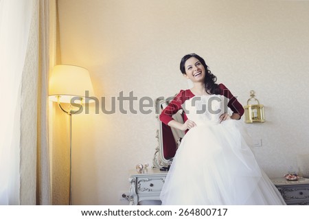 Beautiful, stunning bride, getting dressed in her wedding day. Trying her wedding dress
