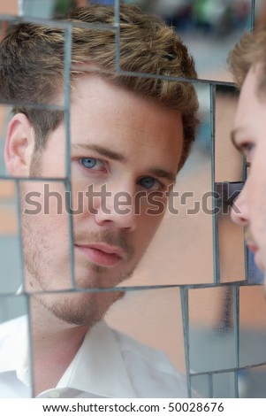 Blonde hair blue eyed man looking at his reflection in mirror