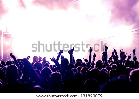 cheering crowd in front of bright purple stage lights