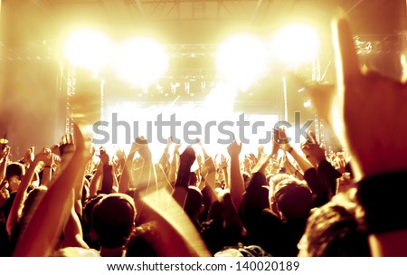 Rock concert, silhouettes of happy people raising up hands