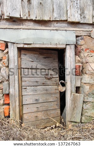 Half opened old wooden door with big rusty padlock