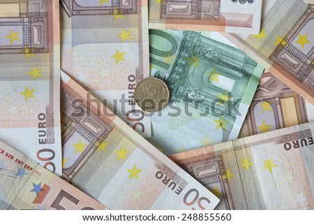 Euro banknotes of fifty and one hundred denomination with twenty cents coin lies over them - money concept and financial background