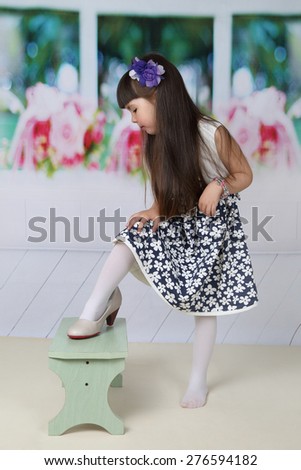 Little girl with long hair tries on mom's shoes - Children want become adults quickly