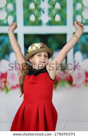 Pretty little girl in hat stretches herself raising hands up in the morning - children beauty and fashion concept