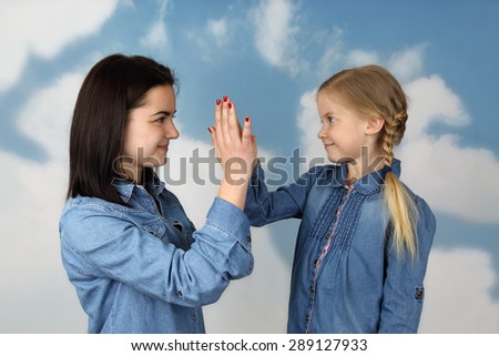 Two sisters, older and younger, greet each other clapping on palm - Family relations and friendship concept