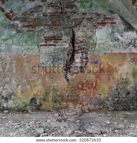Basement of old fortress with rust and moss covered wall and rope on floor- ancient dungeons