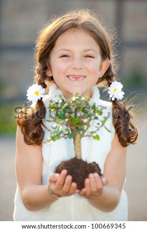 girl holding tree as environmental or nature concept ( focus on child )