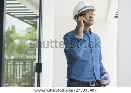 Portrait of  Asian male contractor engineer with hard hat using mobile phone