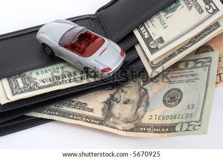 Miniature car over a leather wallet with dollars