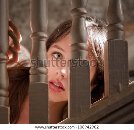 Pretty Young Woman Peeking Out Through Stairway Railings