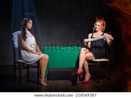 Angel and devil with playing cards on dark background
