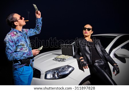 Two gangsters with dollars near the car
