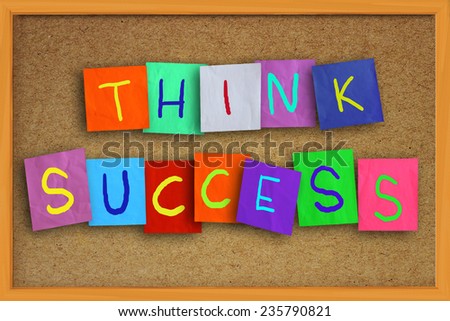 The words Think Success written on sticky colored paper over cork board